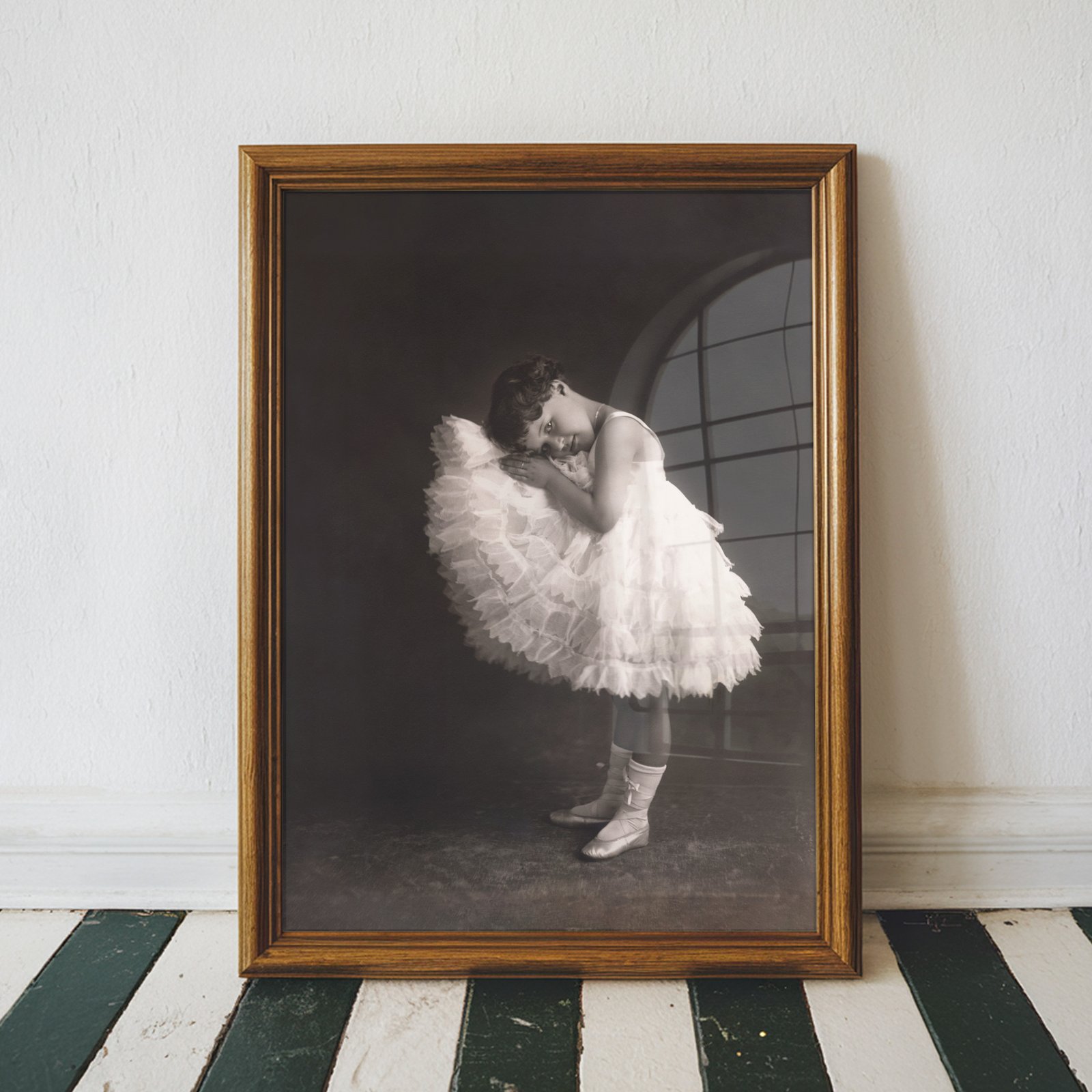 Vintage black and white portrait of a young ballerina in a layered white tutu posing gracefully against a dramatic dark background.