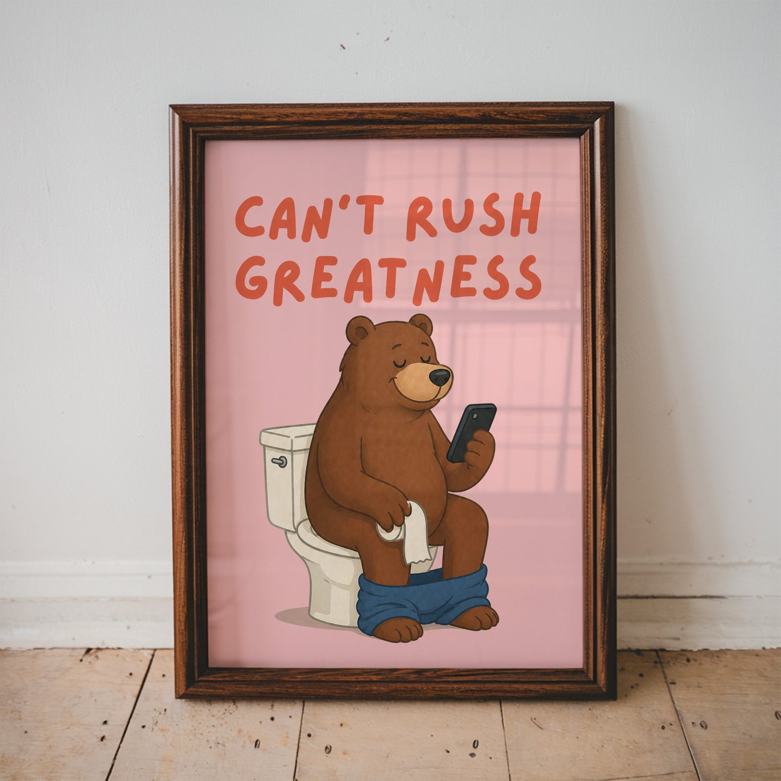 Funny bathroom print featuring a relaxed brown bear sitting on a toilet while looking at a phone with the quote "Can't Rush Greatness."